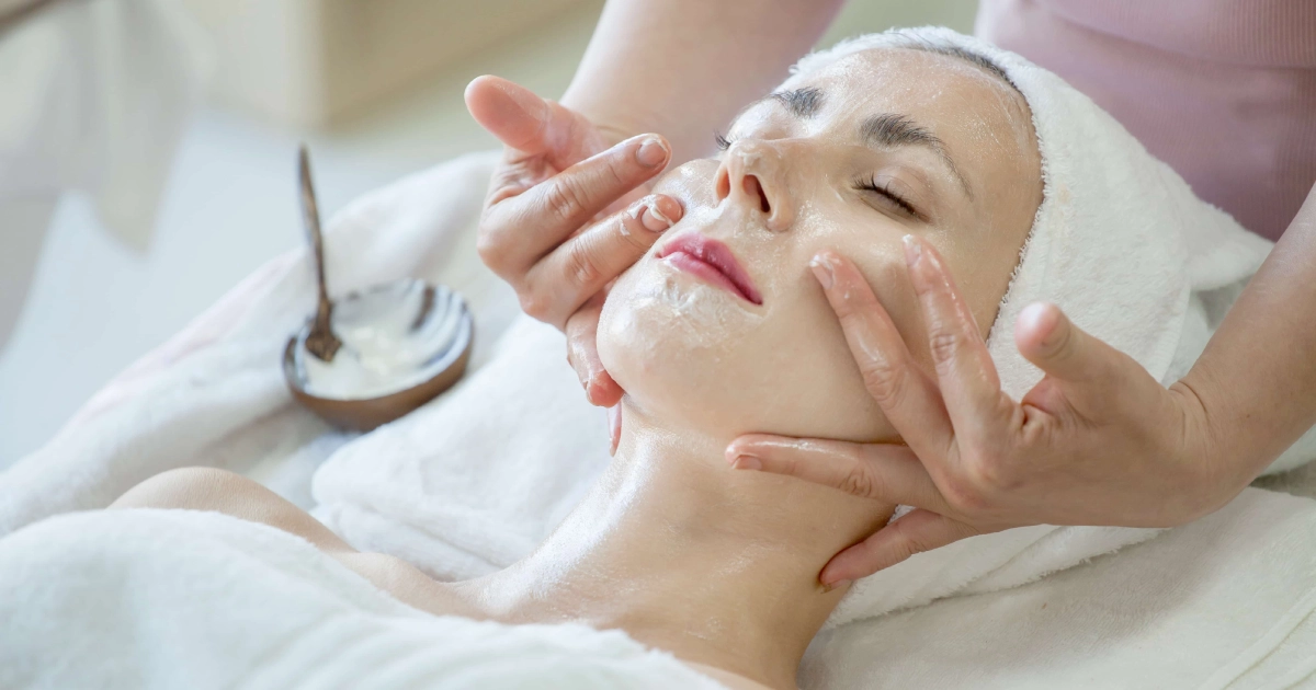 A person lies with eyes closed as a beautician massages a face mask during a Relaxation Facial in Tampa, FL.